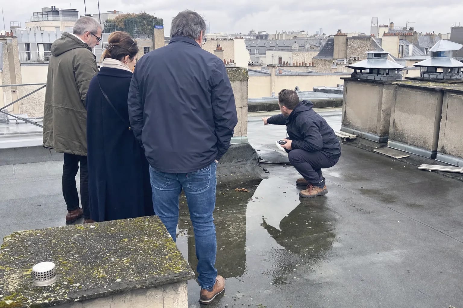 Membres d'un conseil syndical visitant une toiture-terrasse avec un expert bâtiment